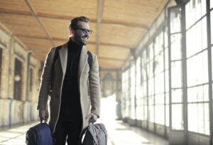 A sense of adventure awaits. A man with luggage looks out a window, ready to explore a new destination