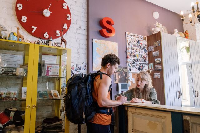 Learning the local language can help you navigate travel situations, such as checking in at a hostel and communicating your needs. Image of a man checking in at the reception desk