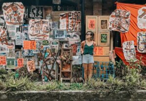 Engage with local artists by learning the language! Image of a woman selling street art on a city street, showcasing the importance of language for cultural immersion